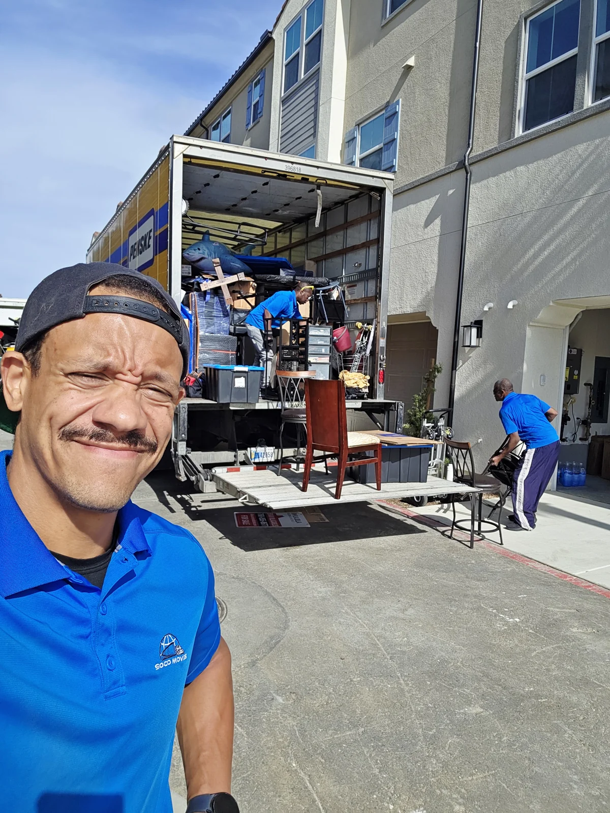 A uniformed Soco Moves team member with crew loading furniture behind him.